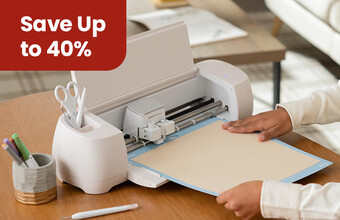 A cricut machine being set-up to cut some vinyl. A save up to 40%' badge. Clicking leads to cricut products