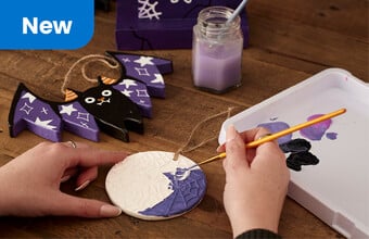 A lifestyle image with a person painting a Halloween ceramic decoration. Clicking leads to Halloween page.